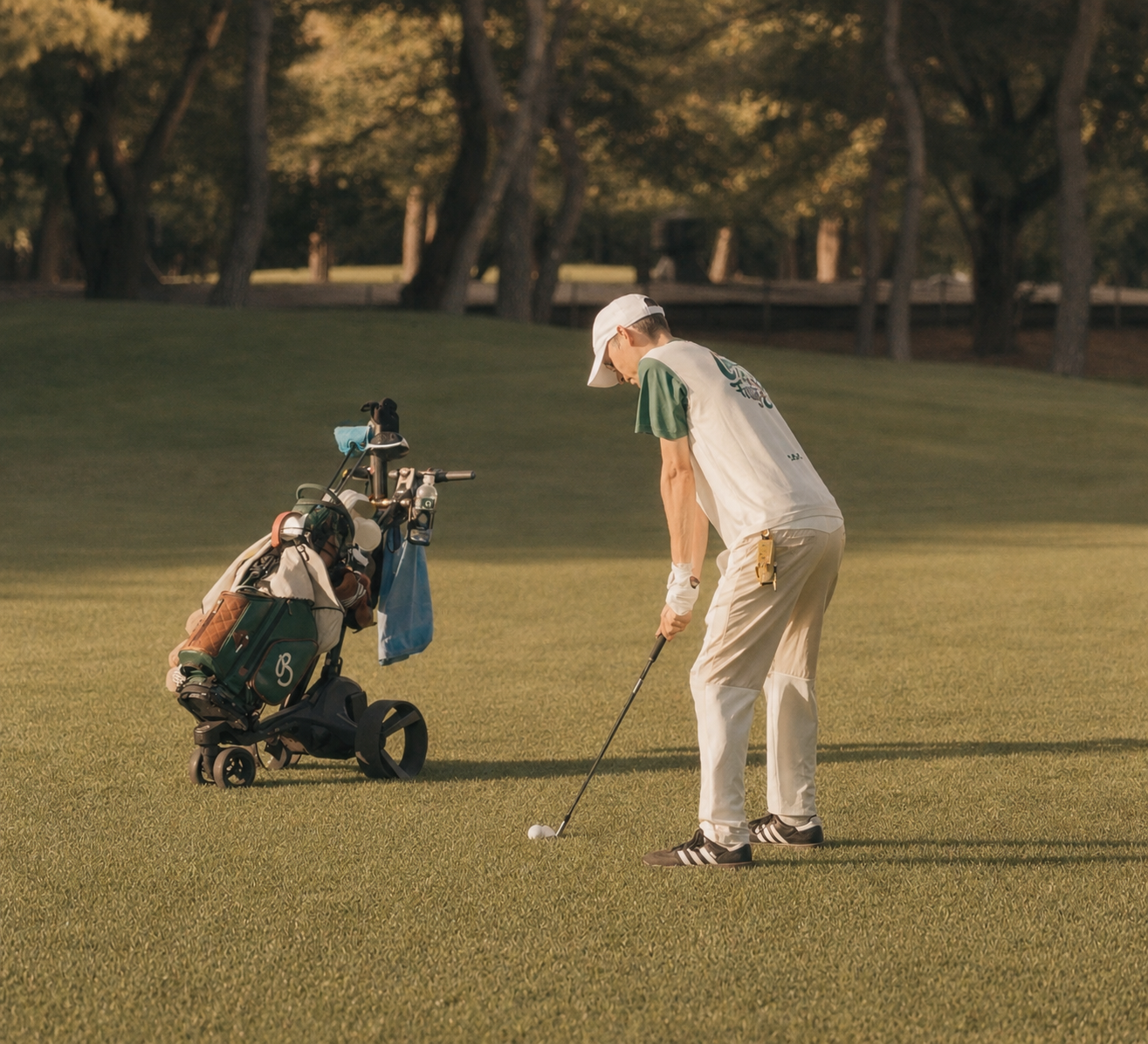 Jean-Baptiste Dominguez addressing a chip shot on the fairway, pine trees in the background.